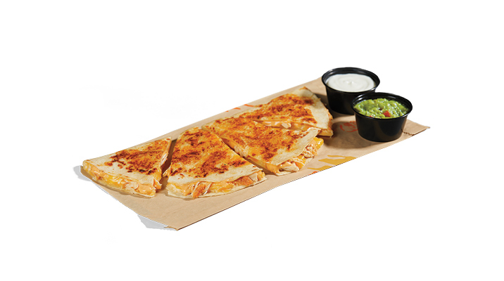 A chicken quesadilla with cups of sour cream and guacamole next to it.