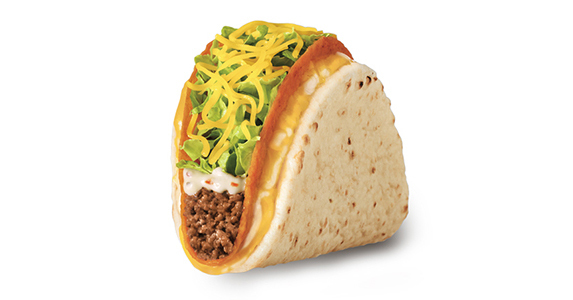 A distressingly orange hard shell taco filled with ground beef, sour cream, lettuce, and cheese. There is a tortilla wrapped around the hard shell taco with a layer of cheese between the two.
