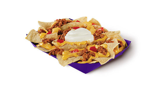 A basket of corn tortilla chips with cheese sauce, ground beef, diced tomato, and sour cream on top.