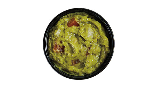 A dipping sauce cup half full of guacamole.