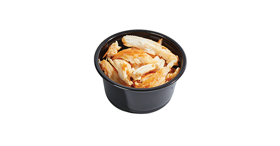 A dipping sauce cup filled with pieces of chicken.