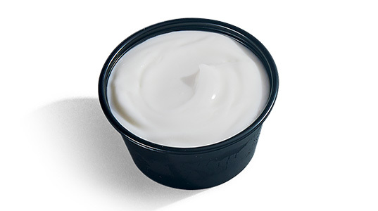 A dipping sauce cup filled with sour cream.