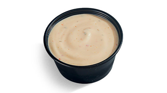 A dipping sauce cup full of spicy ranch.